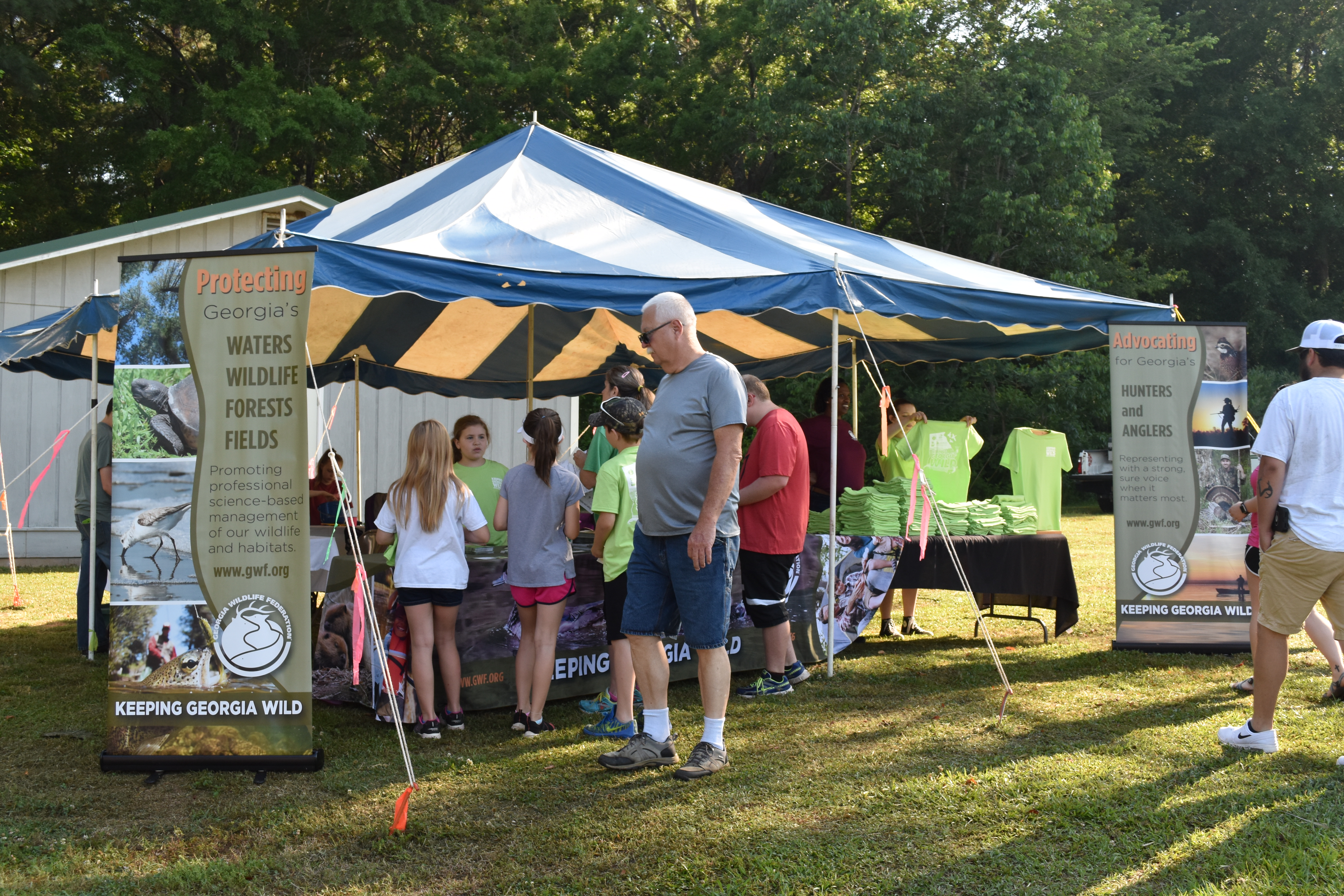 A small group of children gather under a tent to check in for the Georgia Wildlife Federation event.